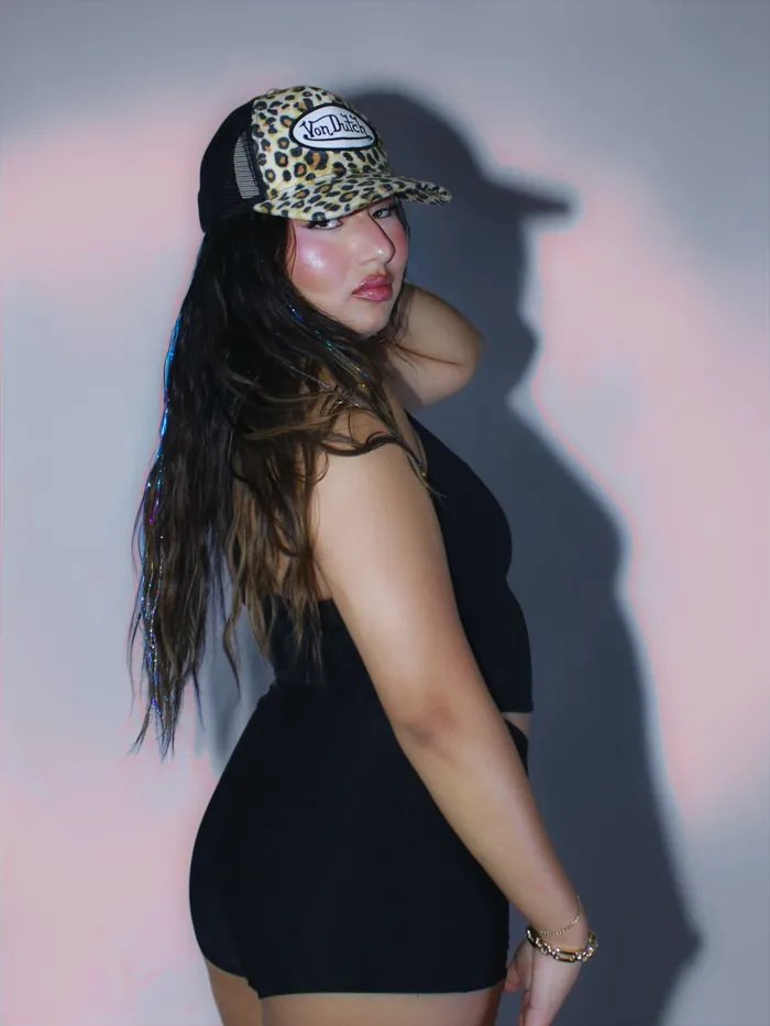 Portrait in a leopard-print cap, split pink and blue gel light, hard shadow