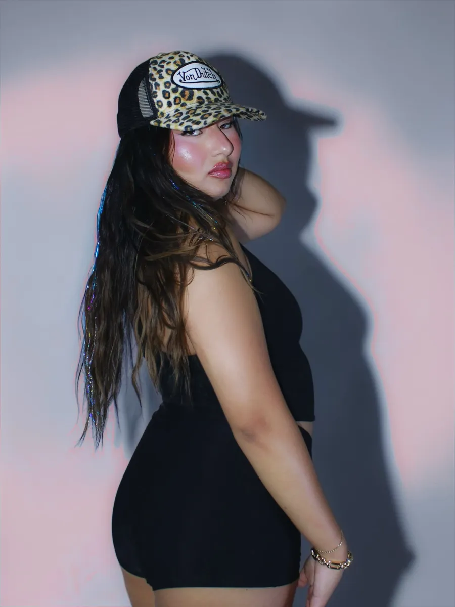 Portrait in a leopard-print cap, split pink and blue gel light, hard shadow