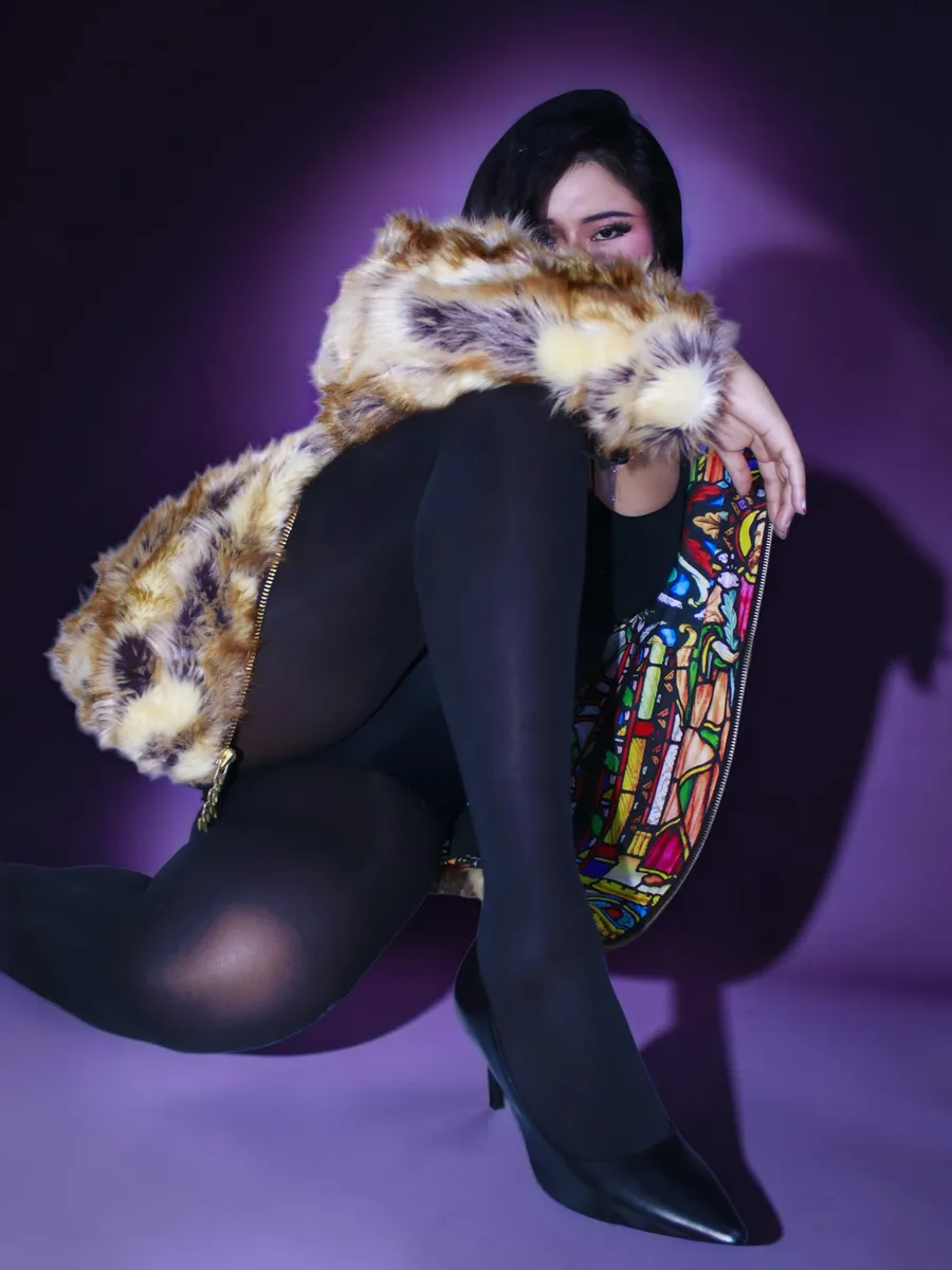 Seated portrait in fur coat and heels under a purple spotlight