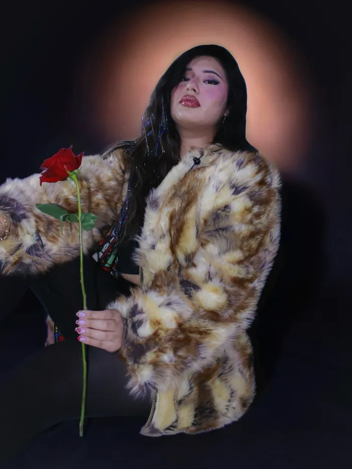 Portrait holding a rose against a red star-print backdrop