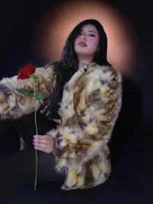 Portrait holding a rose against a red star-print backdrop