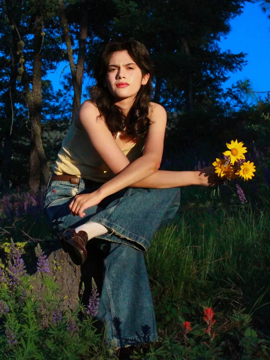 Seated portrait with sunflowers in wildflowers at dusk