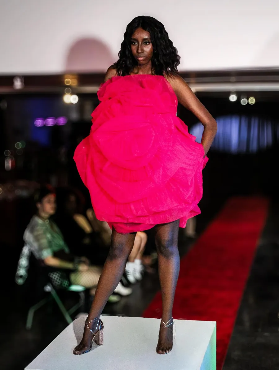 Runway look in a hot pink dress, caught mid-motion