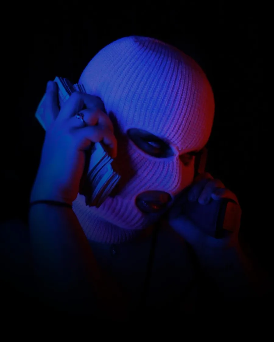 Portrait in a ski mask on the phone, split blue and red light