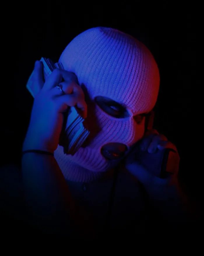 Portrait in a ski mask on the phone, split blue and red light