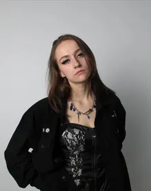 Portrait in a black lace corset against a white wall